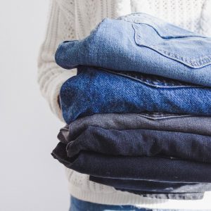 A woman holding a pile of denim jeans