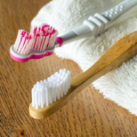 A photo of a plastic and a wooden toothbrush 